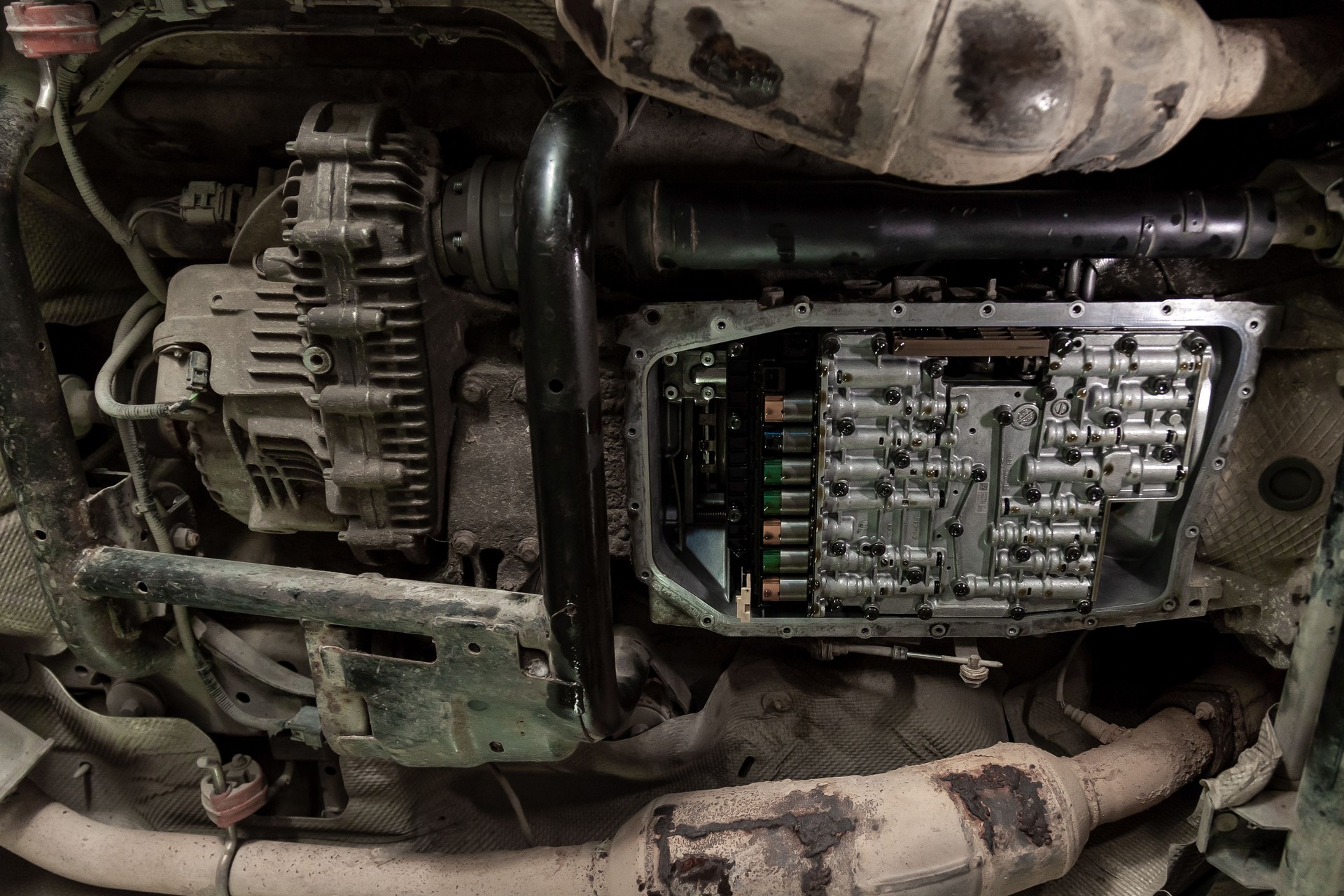 Bottom view of the bottom of the car with the transmission pan removed and a view of the solenoids lubricated with oil during repair and maintenance in the workshop for vehicles.