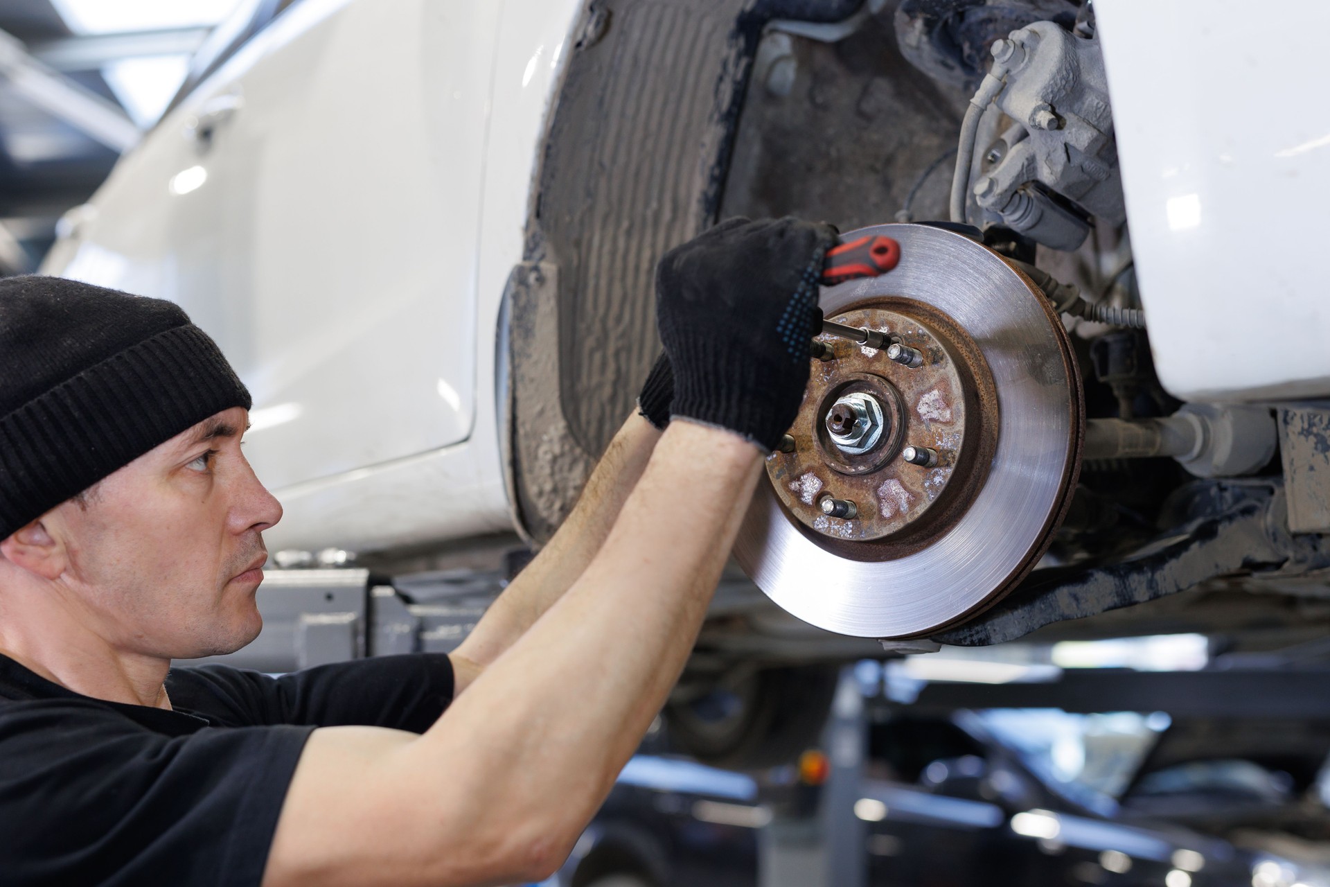 Auto mechanic installing car front brake caliper and brake pads.