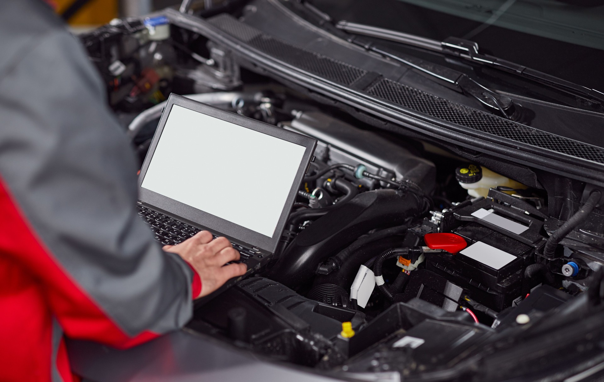 Mechanic using laptop during car engine diagnostic