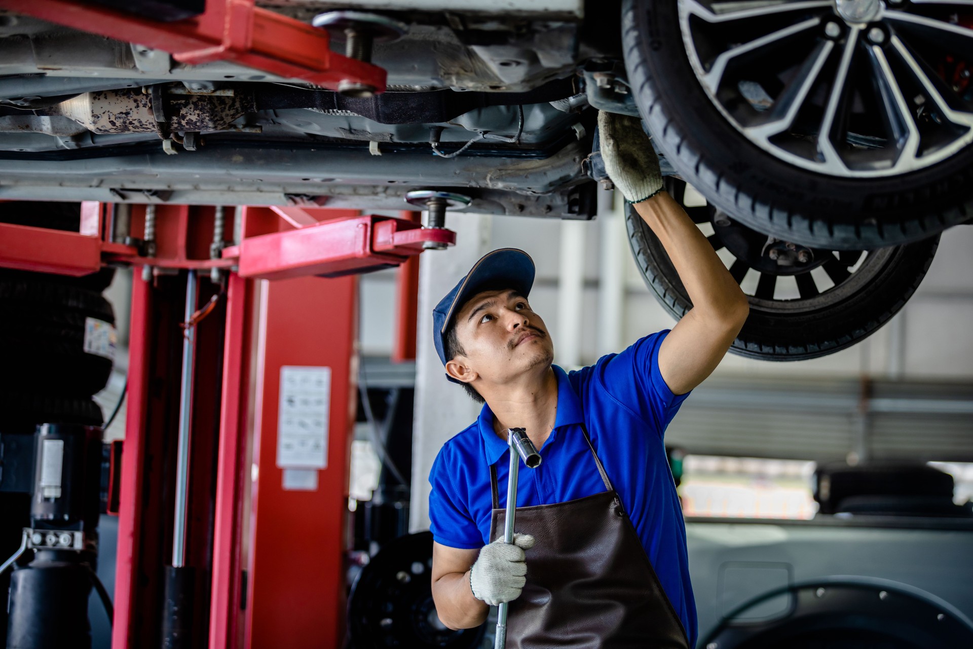 Auto mechanic repairman using a socket wrench working auto suspension repair in the garage, change spare part, check the mileage of the car, checking and maintenance service concept.